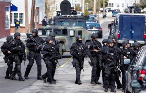 Heavily armed police continue to patrol the neighborhoods of Watertown, Mass. Friday, April 19, 2013, as they continue a massive search for one of two suspects in the Boston Marathon bombing. A second suspect died in the early morning hours after an encounter with law enforcement. (AP Photo/Craig Ruttle)